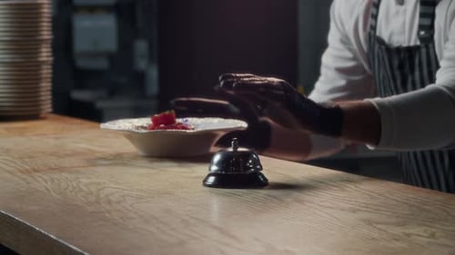 Chef Ringing Service Bell when Sending out Dish to Waiter in Restaurant