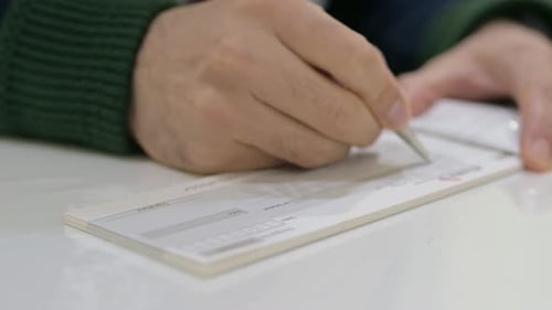 Hands writing on a cheque in Bank