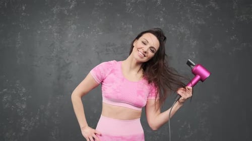 Attractive Woman Dries Hair in Studio with Pink Dryer