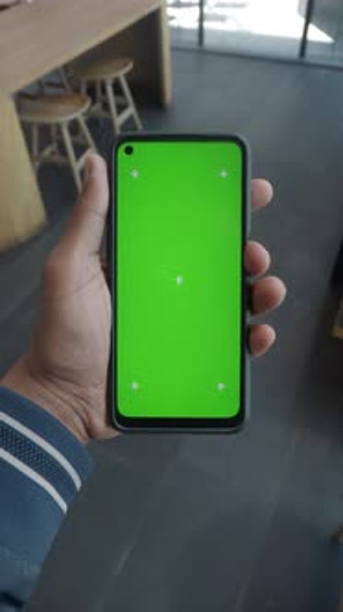 Hand Holding Smartphone with Green Screen Indoors