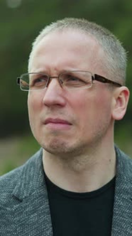 Man in Glasses and Jacket Looking Thoughtful