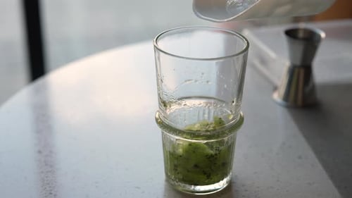 Adding Ice to Kiwi Drink in Clear Glass