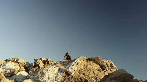 A man climb up the mountain and raise his arms reaching the top