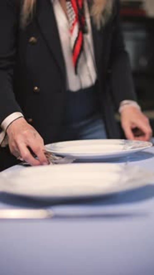 Woman Places Silverware at Table Setting for Dining