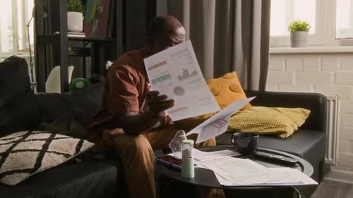 Hombre afroamericano que examina las facturas vencidas en su casa