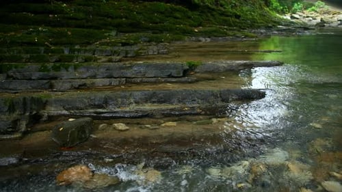 Clear stream running through stone boulders. Creative. Calm river flowing on stone bottom