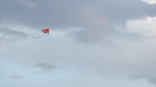 Farbenfroher Drachen, der gegen einen grauen Himmel fliegt, niedriger Winkel