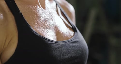 Close up of the body of a sporty and fit woman, who recovers her energy after sweating at the end