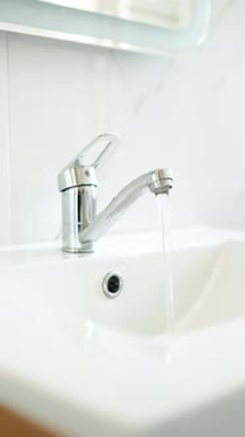 Running Faucet Water in Bathroom Sink in Home