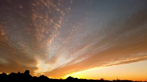 Motion time lapse video of richly colored and textured clouds near a setting sun in the Arizona dese