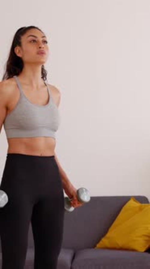 Young Woman Exercising at Home with Weights