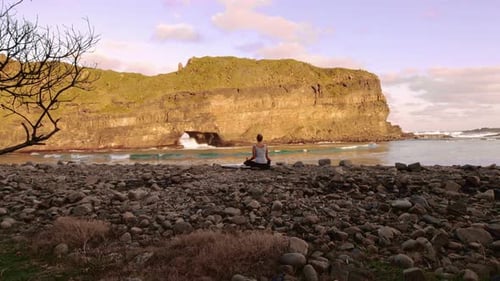 Gesunde junge unabhängige Yoga-Praktizierende, die Meditation praktiziert und auf Pebble Bea posiert...