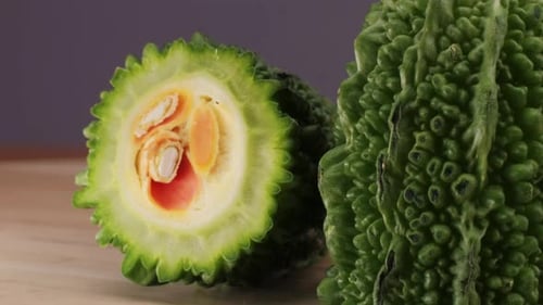 Une gourde amère, un légume souvent utilisé comme ingrédient en cuisine, est posée sur une table en bois.