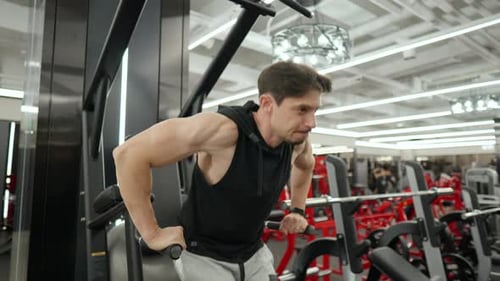 Parallel Bar Dips. Mid age Muscular Man Trains Lower Chest Doing Exercises in Health Club