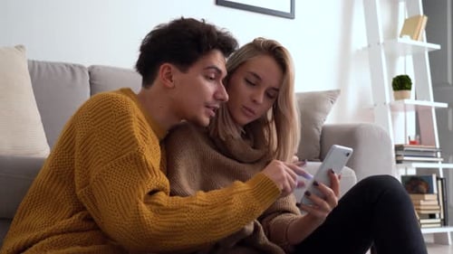 Happy Couple Using a Smartphone in Living Room