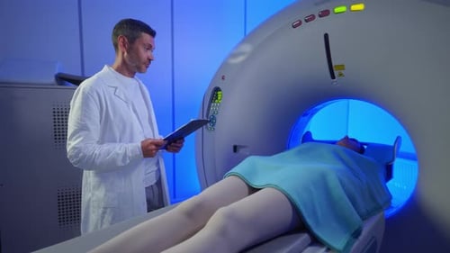 Medical Worker Standing Confidently Near MRI Tunnel While Female Patient Resting on Table Overseeing