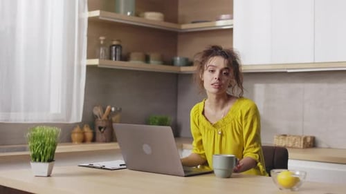 Young Woman Typing and Smiling in Kitchen