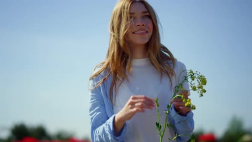 Happy Woman with Long Beautiful Hair Holding Wild Plant in Blue Sky