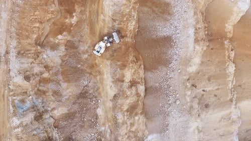 An Excavator Working on a Rugged Mining Site, Digging Through Layers of Soil and Rock to Extract