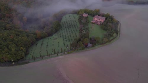 Idyllic Mediterranean style farm house in rural Italy with morning mist, aerial