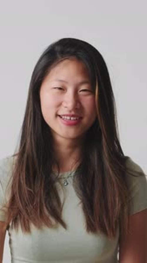 Young woman looking at camera and laughing isolated over white background in studio