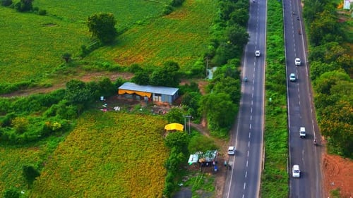 Ariel view of vehicles drives on road between the large land of agricultural farms