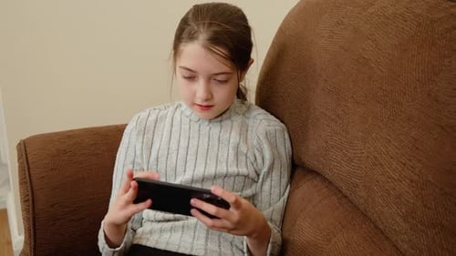 Girl Smiling While Using Mobile Phone on Couch