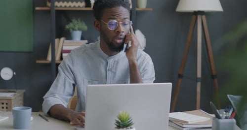 Man on Phone Using Laptop in Home Office
