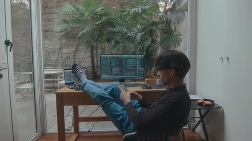 Programmer Using Phone with Feet Up on Desk in Home Office