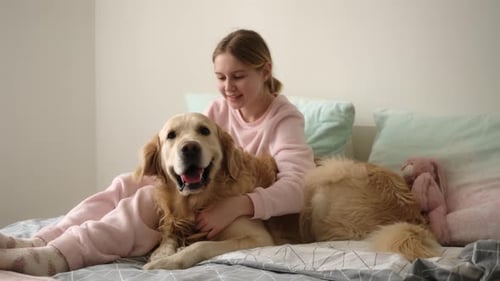 Girl Poses with Her Golden Retriever on Bed
