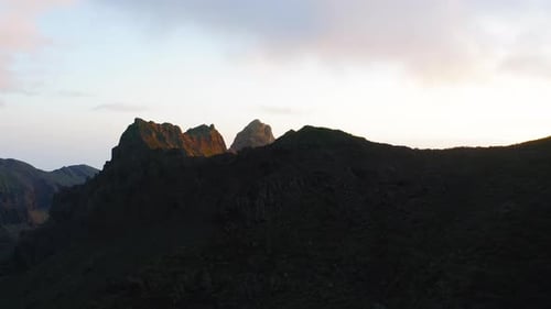 Dark Mountain Silhouette Against Blue Cloudy Sky at Sunset