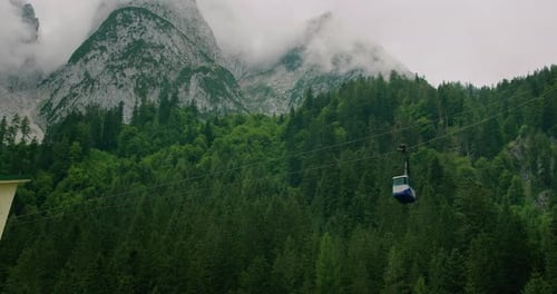 Cable Car Moving Over Dense Green Forests with Misty Mountains in the Background
