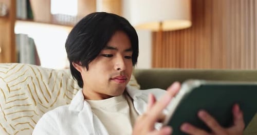 Young Man Relaxing on Couch Using Tablet