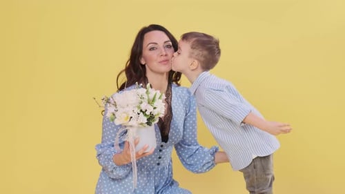 Affectionate Boy Giving Mother Flowers and a Kiss