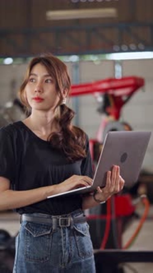 Female engineer standing and using a laptop in a factory