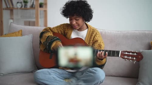 Young Adult Plays Guitar on Couch