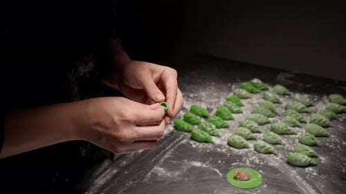 Close Up of Hands Carefully Shaping Vibrant Green Dumplings on a Floured Surface Arranging Handmade