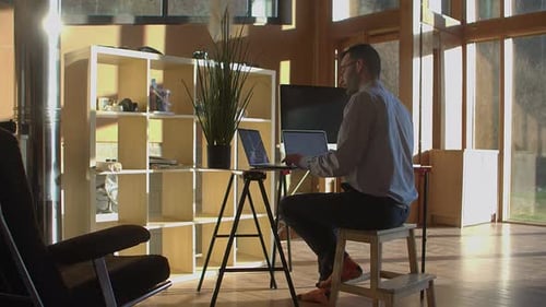 Trading stocks or cryptocurrency from home, back view of male trader and his room, wide angle view w