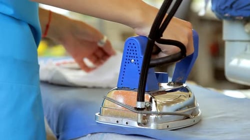 Closeup of a female textile worker ironing garments at a modern factory