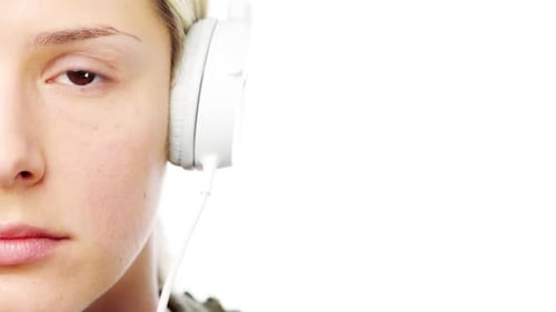 4k-Videomaterial einer jungen Frau mit Kopfhörern vor weißem Studiohintergrund