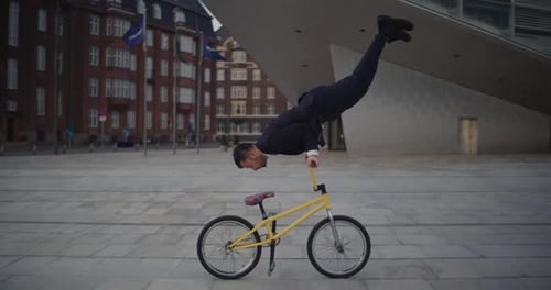 Acrobatic Man Doing Handstand on Bicycle in Urban Area