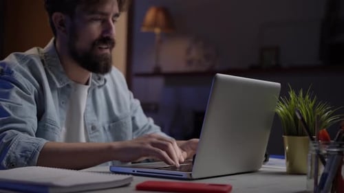 Man Typing on Laptop Computer at Night