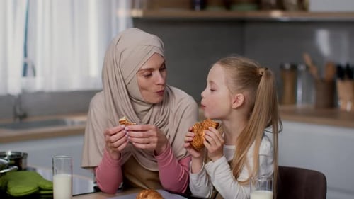 Mother and Daughter Eating Croissants in Kitchen