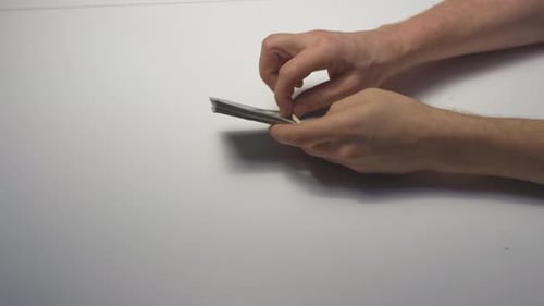 Hands Removing Rubber Band From Wad of Cash