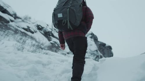 Tourist Climbing Up Snowy Hill and Looking through Binoculars