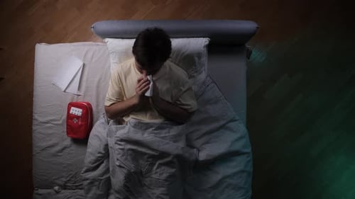 Man Lying in Bed with Cold and Tissues