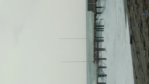 Crashing Waves Underneath Pier on Overcast Day