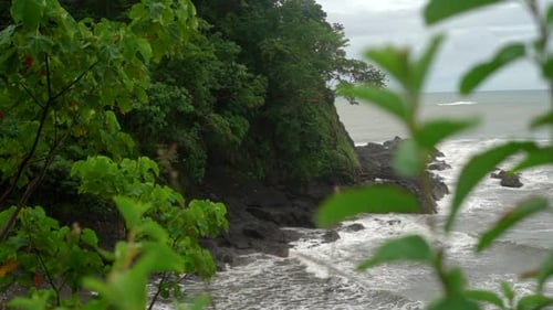 Amazing view of a rocky, tropical shoreline with ocean waves crashing against the rocks and cliff -