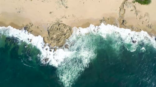 Aerial top view of waves break on rocks. Aerial drone top down view bird eye view of sea blue waves