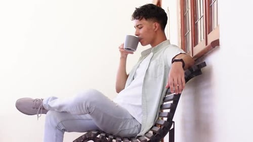 Young Adult Relaxing and Drinking Coffee on Bench